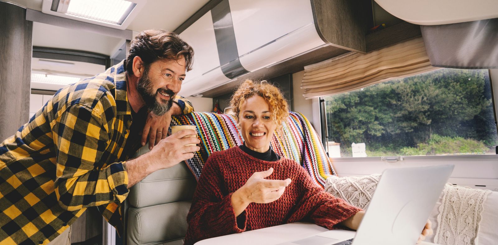 a couple in an RV looking at a laptop