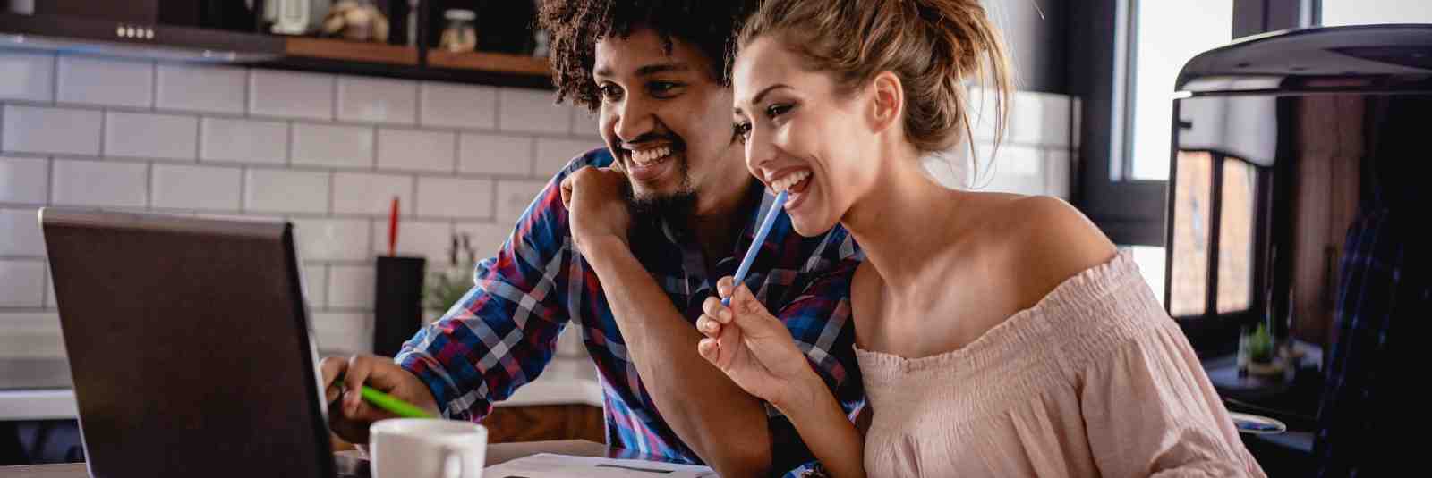 Couple smiling while viewing computer