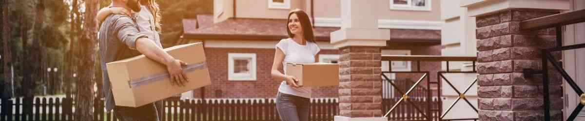 family with moving boxes walking into home