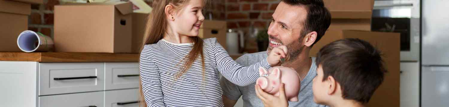 dad helping kids put money in piggy bank