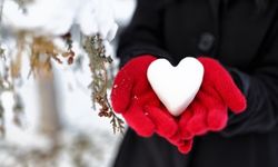 person holding heart snow ball