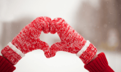 person with winter mittens making a heart with hands